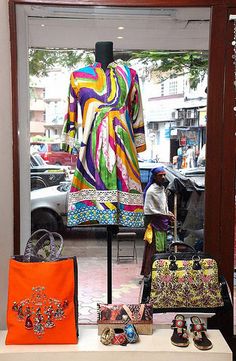 an assortment of handbags and purses on display in a store window with cars behind them