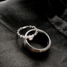 two silver rings sitting on top of a black cloth