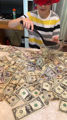 a young boy is playing with money on the table and wearing a red visor