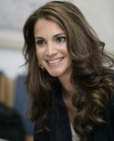 a woman with long brown hair smiling at the camera and wearing a black blazer