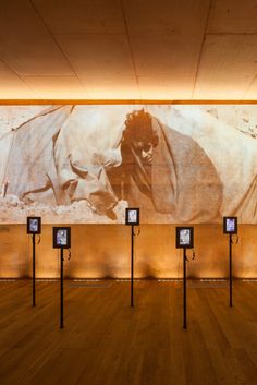 an empty room with wooden floors and pictures on the wall behind them, all lit up by spotlights