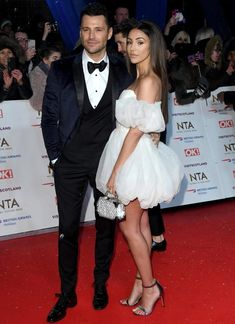 a man in a tuxedo standing next to a woman on a red carpet