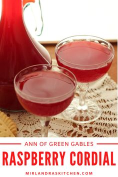 two glasses of raspberry cordial on a doily next to a pitcher