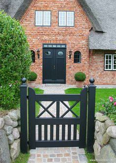 a brick house with a black gate and stone walkway leading to the front door is shown