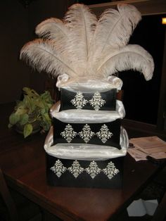 three tiered black and white cake with feathers on top