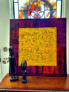 a wooden table topped with a statue next to a stained glass window covered in art