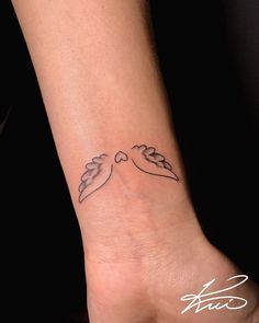 a small tattoo on the wrist of a woman's left hand, with two hearts and leaves