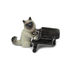 a figurine of a cat sitting next to a black and white toy piano