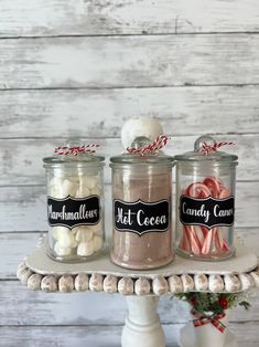 three jars filled with candy canes and marshmallows