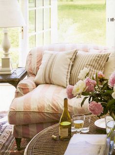 a living room filled with furniture and flowers on top of a coffee table in front of a window