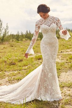 a woman in a wedding dress is walking through the grass with her hand on her hip