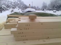 several pieces of wood are stacked on top of each other in the snow near some trees