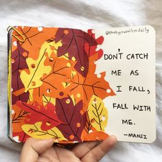 a hand holding an open book with autumn leaves on it and the words don't catch me as i fall with me