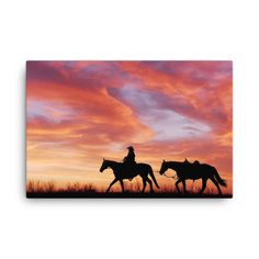 two people riding horses at sunset with the sky in the backgroufft