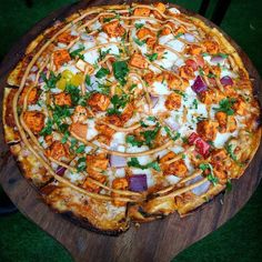 a pizza sitting on top of a wooden cutting board covered in cheese and veggies