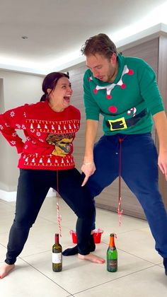 a man and woman in ugly sweaters playing with bottles