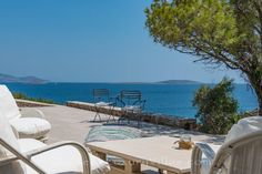 there are chairs and tables on the patio by the water with an ocean view in the background