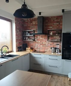 a kitchen with white cabinets and brick wall behind the countertop, along with a wooden floor