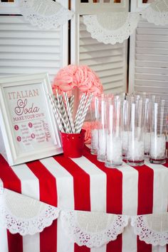 there is a red and white striped table cloth with glasses on it that have candy in them