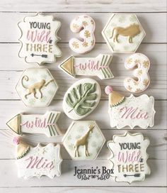 decorated cookies are arranged in the shape of animals and numbers on white wood boards with pink lettering