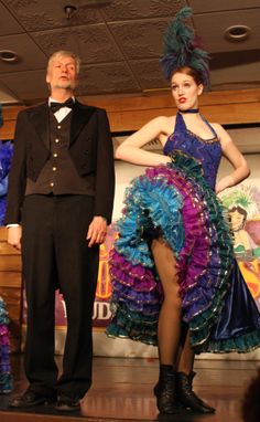 a man and woman standing next to each other in front of a stage with dancers