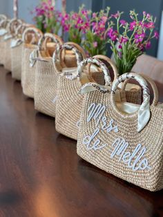 three straw purses sitting on top of a wooden table with flowers in the background