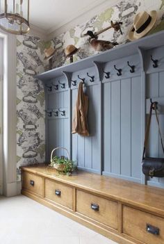 a wooden bench sitting in front of a wall with coat racks on top of it