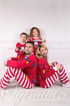 a man and two children in matching pajamas are posing for a family photo with christmas lights all around them