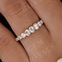 a woman's hand wearing a gold ring with five diamond stones on the band