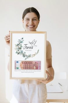 a woman holding up a framed poster with the words tenas written in cursive writing