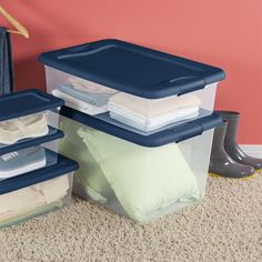 three plastic storage containers stacked on top of each other next to a pair of rubber boots