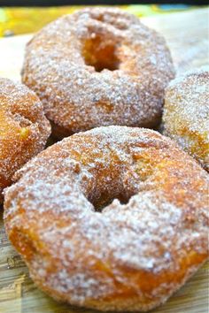 several sugar covered donuts sitting on top of a wooden cutting board