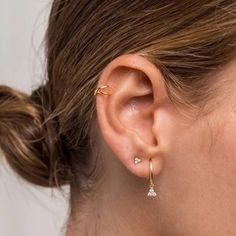 a close up of a woman's ear with two small diamond earrings on it