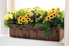 sunflowers are in a wooden box on the window sill