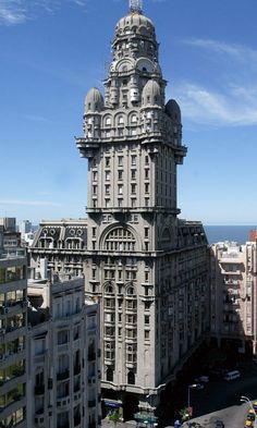 a very tall building in the middle of a city with lots of buildings around it