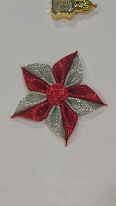 two christmas decorations on a white surface with one red and the other silver in color