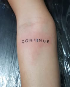 the word continue is written in black ink on a woman's arm