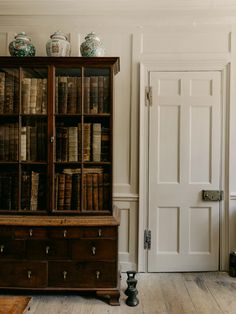 an old bookcase with many books on top of it in front of a white door