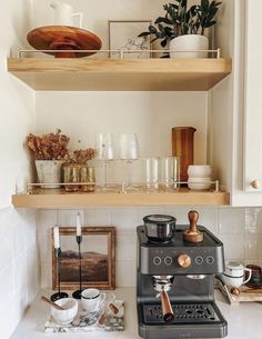 an espresso machine sitting on top of a counter next to some plates and cups