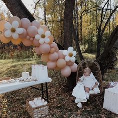 a baby sitting in a chair next to a bunch of balloons