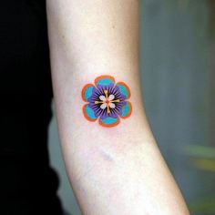 a small flower tattoo on the wrist is shown in blue, orange and pink colors