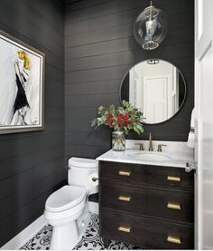 a white toilet sitting next to a bathroom sink under a mirror on top of a wooden cabinet