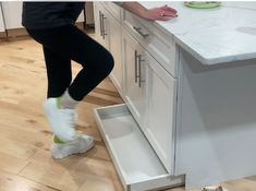 a person standing on the kitchen floor with their feet in an open drawer