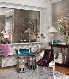 a living room filled with lots of furniture next to a wall covered in mirrored walls