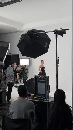 a group of people in a room with cameras and umbrellas on the floor,