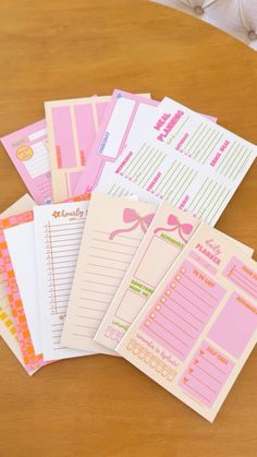 several pink and white papers on top of a wooden table