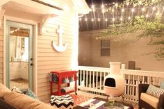 an outdoor living room with lights strung from the ceiling and furniture on the front porch