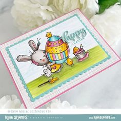 a close up of a card with flowers in the background and a bunny holding an egg