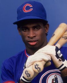 a baseball player holding a bat in his right hand and wearing a hat with the chicago cubs on it