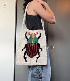 a woman is holding a crocheted bag with a ladybug on it